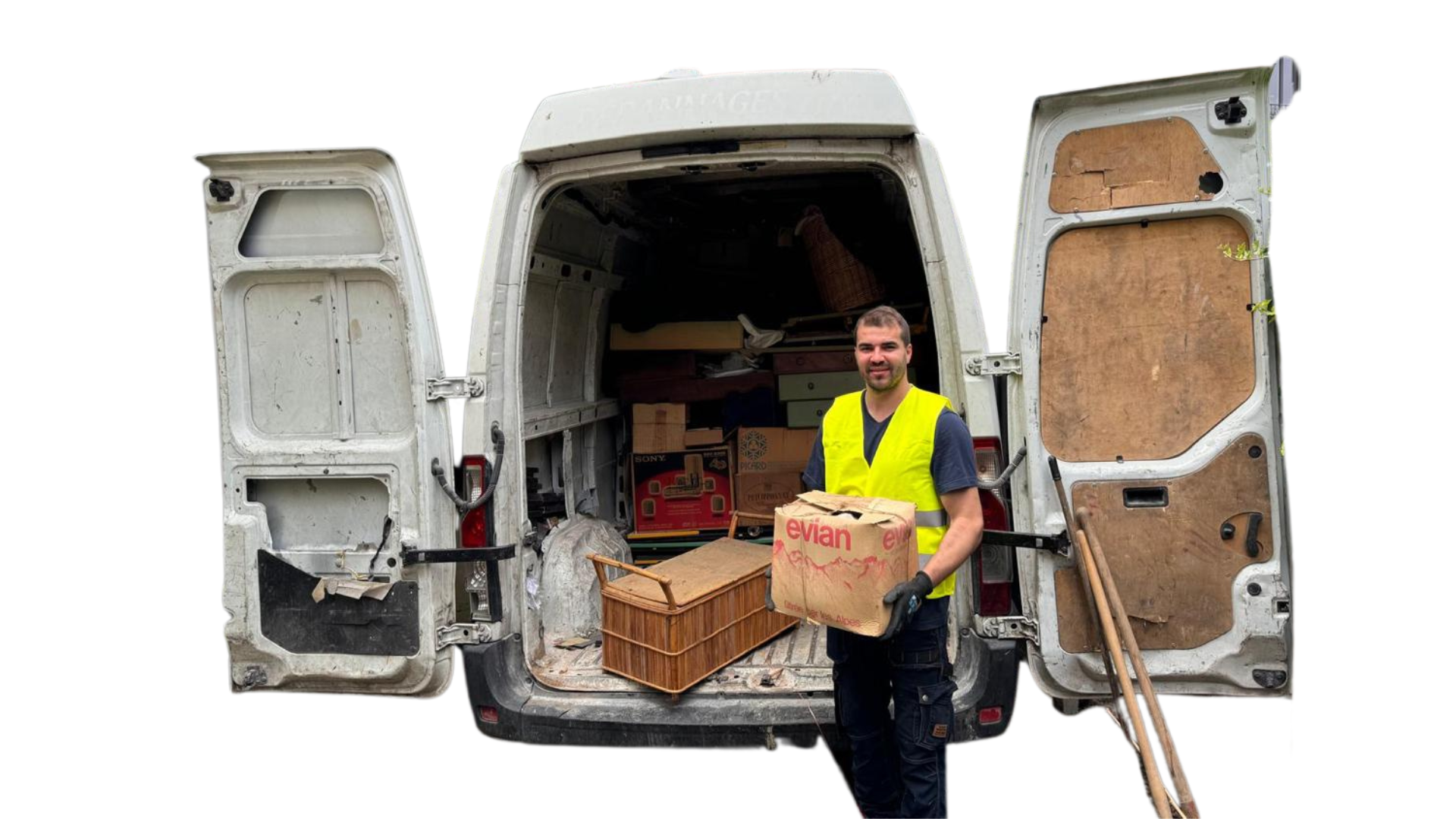 Un employé de DND Services tenant un carton Evian devant un camion de débarras chargé d'objets divers.